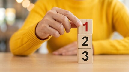 a close up shot showcases a hand gently interacting with wooden blocks stacked with the numbers one two and three displayed prominently on each cube