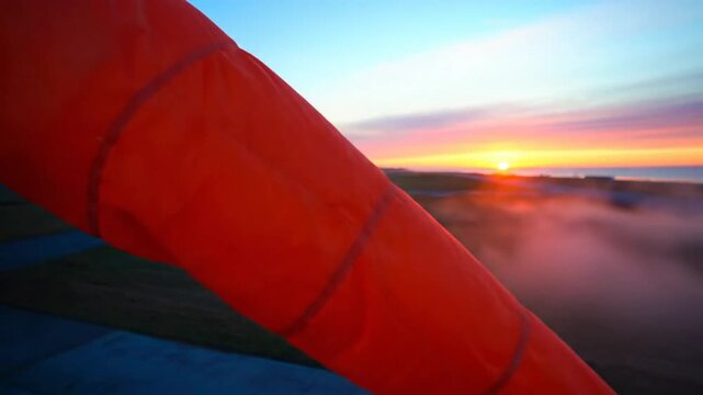 Bright orange windsock blowing gently in the wind with the beautiful sunrise behind