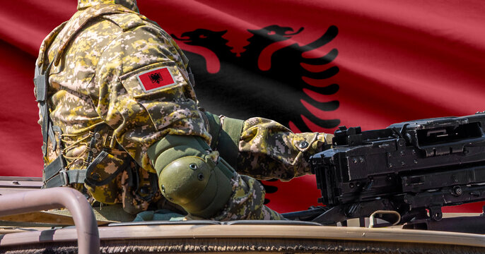 Albania flag with soldier at machine gun turret in front of it. Closeup side view.