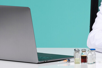 Medical Research Workspace with Laptop Computer and Vaccine Vials on White Desk