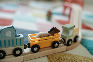 Wooden toy train on a railway track during children’s playtime at home. Educational toys that support creativity, imagination and early childhood development. Cozy indoor lifestyle concept.