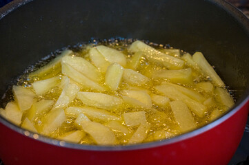 Potato fries sizzling in hot oil in a pan