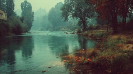 A tranquil river meanders through a hazy, autumnal landscape