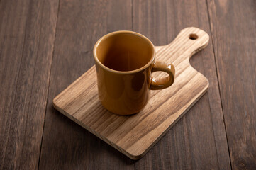 ウッドテーブルに置かれたマスタードカラーのマグカップとカッティングボード