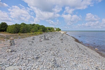 Fototapeta premium Scenic view of a shingle of pebble beach, with numerous man-made stone cairns (piles) built by visitors in summer with clouds on the sky, Tagaranna, Saaremaa, Estonia.