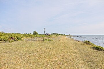 Rocky coastal landscape with former Soviet border guard post or watchtower and building in the background in summer with blue sky with light clouds, Türju, Saaremaa, Estonia.
