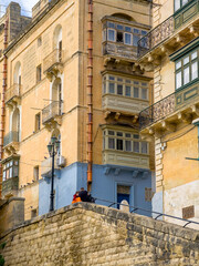 Valletta old town narrow street with traditional Maltese balconies and limestone facades
