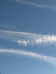 Azure canvas above, painted with delicate feathery cloud formations stretching across the vast