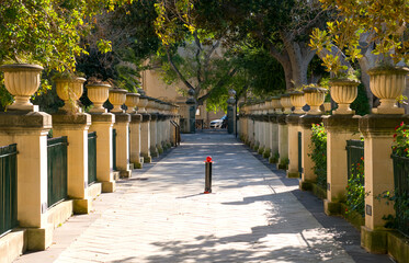 Upper Barrakka Gardens, Valletta, Malta - tree-lined pathway framed by classical urns and shaded terraces