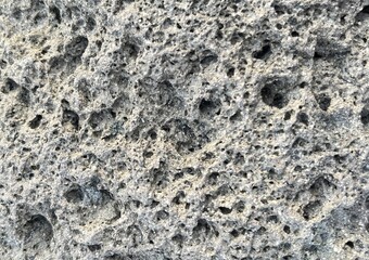 Macro texture of porous grey volcanic rock. Detailed natural basalt stone surface with organic holes and rough mineral grit.
