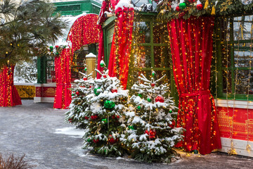 Moscow, Russia - 30 December 2025: Snow covered Christmas trees and red curtains with lights along festive pavilion,