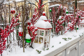  Row of snow covered lanterns and red berry branches with Christmas baubles along winter fence, Moscow, Russia.
