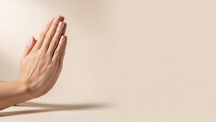 Close up of human hands pressed together in a prayer or gratitude gesture against a soft warm beige background, minimalist photography.
