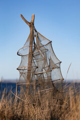 Traditionelle Reusen- bzw. Fischernetze an Holzpf&auml;hlen in den D&uuml;nen am Timmendorfer Strand an der Ostsee. Die leeren Netze h&auml;ngen ruhig im Wind vor blauem Himmel und vermitteln maritimes Handwerk