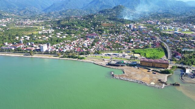 Aerial suburb view near Batumi from sea. 4K horizontal drone footage in clear weather shows residential districts, private houses and a busy road with cars along the Georgian coastline.