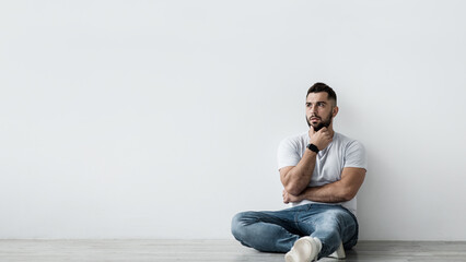 Young european bearded man, regrets something. Sad shocked unhappy pensive handsome guy sit on...