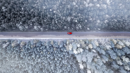  Car rides on the road in the winter forest top view from the drone.