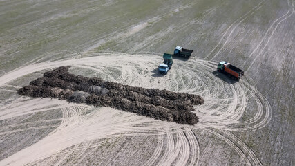 Trucks carry on the field of organic fertilizer with aerial photography drone. Agriculture