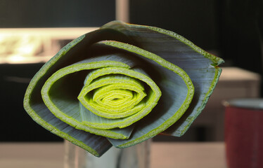 close up of a leek stalk, blurred kitchen in the background. Vegetable, vegetarian, food and drink concept.