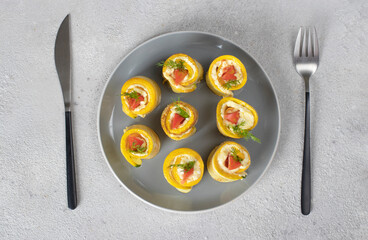 Zucchini rolls with garlic, cream cheese and tomato on gray plate