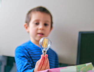 Boy Carefully Holding a Clear Filament Lightbulb as a Concept for Science Discovery