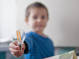 Child Holding Out a Filament Lightbulb Toward Camera as a Concept for Innovation - The Big Idea, Client Solutions, or Creative Brainstorming
