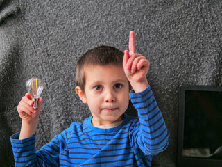 Boy Raising Finger with Lightbulb Representing a Brilliant New Idea - Pointing Up with an Idea Gesture - Child Holding a Filament Bulb and Raising a Finger
