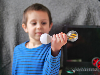 Young Boy Comparing LED and Filament Lightbulbs for Science Learning
