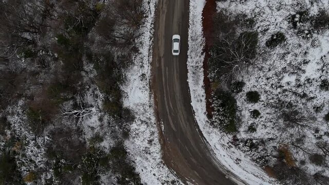 A winter road scene featuring fresh car tracks leading through snow-covered surroundings. The composition conveys movement, journey, and solitude, with a cold seasonal atmosphere and quiet winter land
