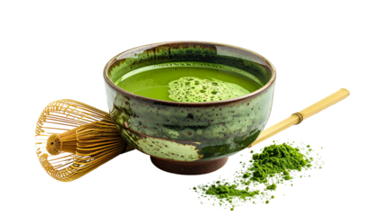 A ceramic bowl of frothy green beverage, whisk, and powdered green tea on a dark background