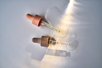 Skincare pipettes dropping cosmetic serum liquid on surface
