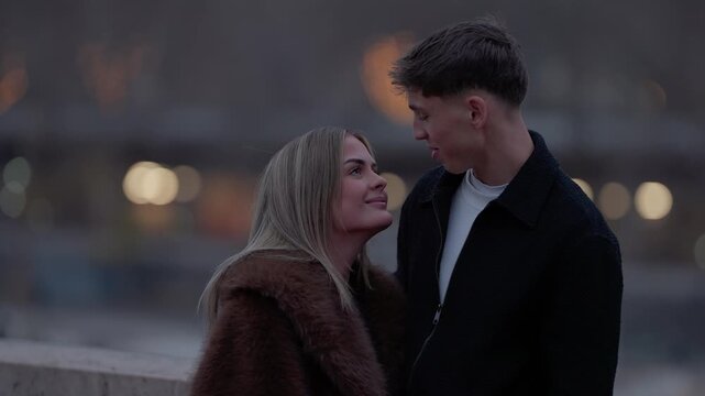 A romantic couple in Paris France looks at each other with love and affection The scene is set in the evening with soft lighting and bokeh lights in the background The couple is embracing and sharing 