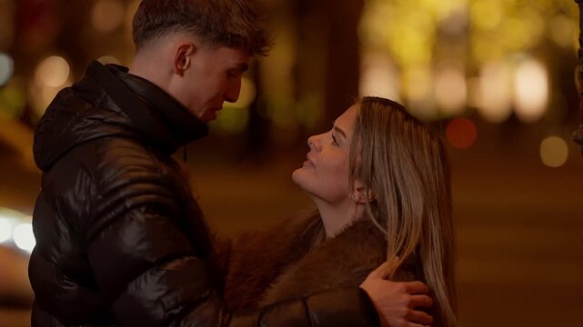 A romantic couple kisses in Paris France at night The young lovers embrace in the city of love with soft focus lights in the background The scene evokes romance love and affection.