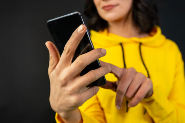 Close-up of a woman looking at a smartphone against a black background.