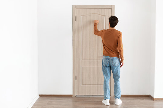 A young man stands at a wooden door, knocking gently with his back turned. He is clothed in a simple outfit, wanting to enter a room. The setting is minimalistic and inviting.