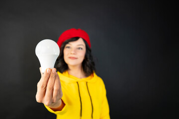 A woman holding a light bulb against a black background. Creative idea concept.