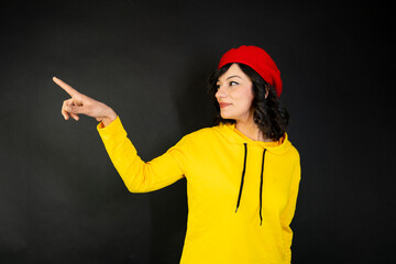 A woman pointing to an empty space against a black background. Advertising and creative thinking.