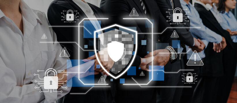 A diverse group of professionals standing together in a modern office, emphasizing cybersecurity through a digital shield icon, representing the need for protection and vigilance. Trope - Powered by Adobe