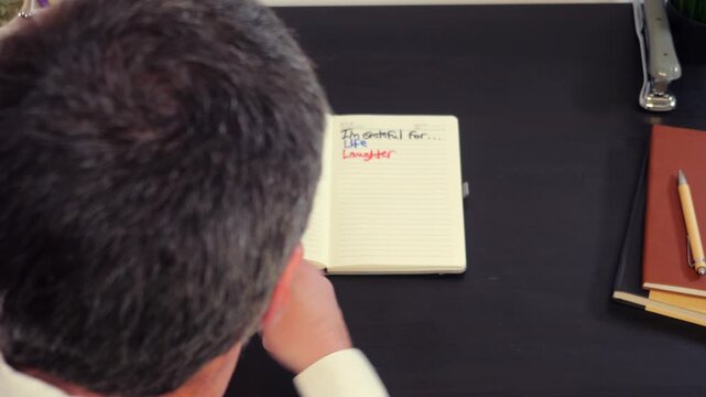 Gratitude List Journals Concept - Gray Haired Middle Aged Man Writes in Journal About What He is Grateful and Thankful For in Life