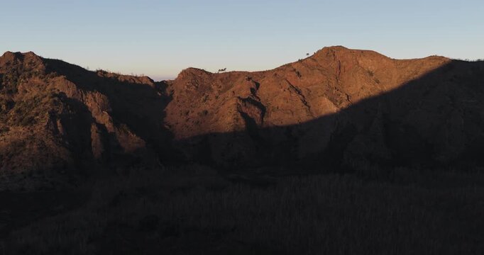 Aerial view of the rugged Mount Vesuvius at sunset, with its peaks bathed in golden light contrasting with the deep shadows, Ercolano, Campania, Italy.