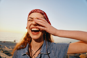 Lifestyle woman in modern boho-western denim street style laughs joyfully under warm sunlight with...