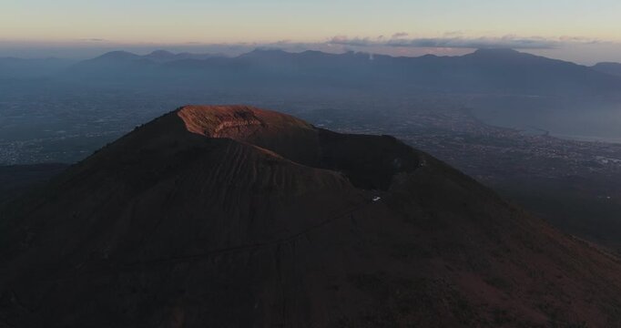 Aerial view of the majestic Mount Vesuvius crater, its slopes casting long shadows under the fading light, Ercolano, Campania, Italy.