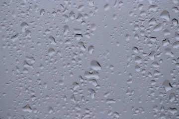 Transparent plastic texture with water drops. Transparent white plastic background. Wet transparent polyethylene film with droplets of water after rain. Water drops close-up.