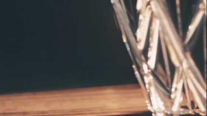A video showcasing a close-up view of a crystal glass with intricate designs reflecting light in a dark room