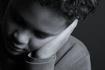 deaf boy and suffering from deafness and hearing loss on black grey background with people stock photo stock image	