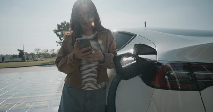 Business woman use smartphone application EV car charge outdoor station sustainability transport technology