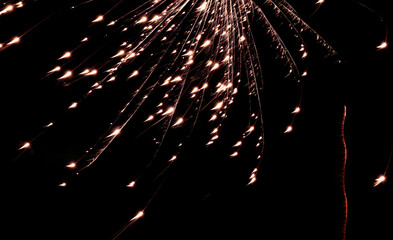 Faint fiery streaks cascade downward, Soft amber sparks drift through night sky