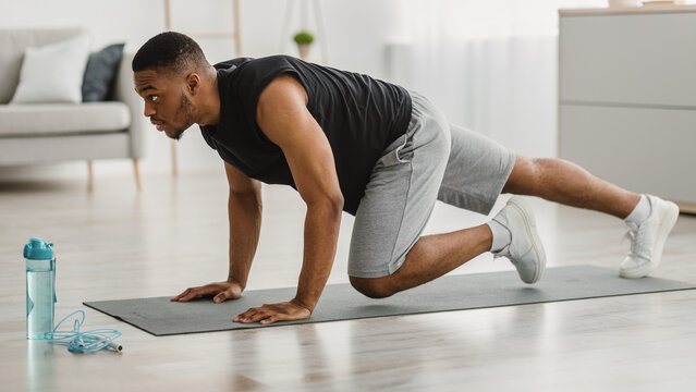 Sporty African American Man Doing Running Plank Exercise At Home. Side View Of Athletic Guy Training In Living Room. Male Fitness Workout And Bodybuilding. Sport Motivation Concept. Panorama - Powered by Adobe