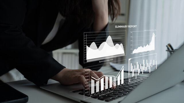 A business professional engaged in analyzing digital reports on a laptop, featuring various data visualizations including graphs and charts in a modern office setting. Impute - Powered by Adobe