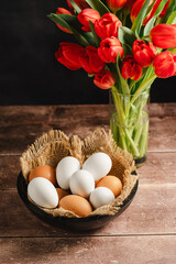 Easter eggs and red tulips bouquet. Festive Spring background for greeting cards.
